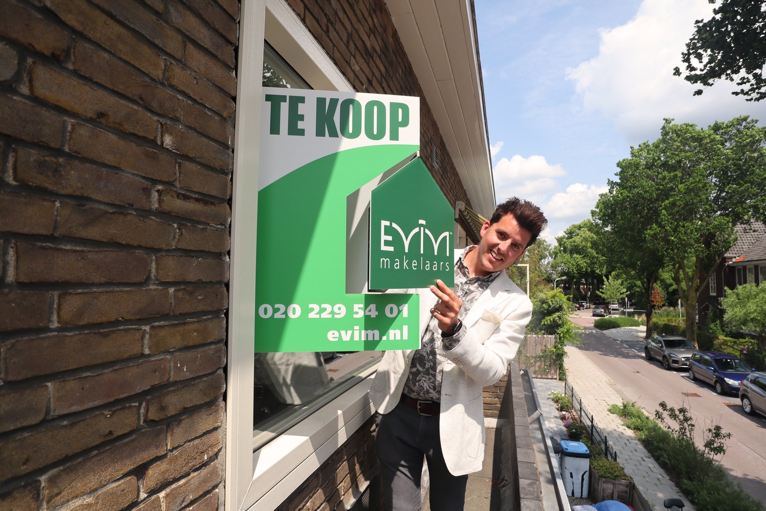 Evim makelaar plaatst een Te Koop-bord bij een woning